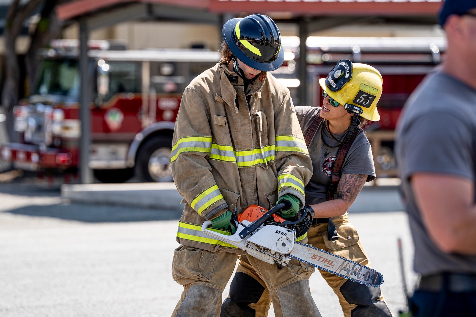 a camper using a chainsaw with a firefighter's supervision