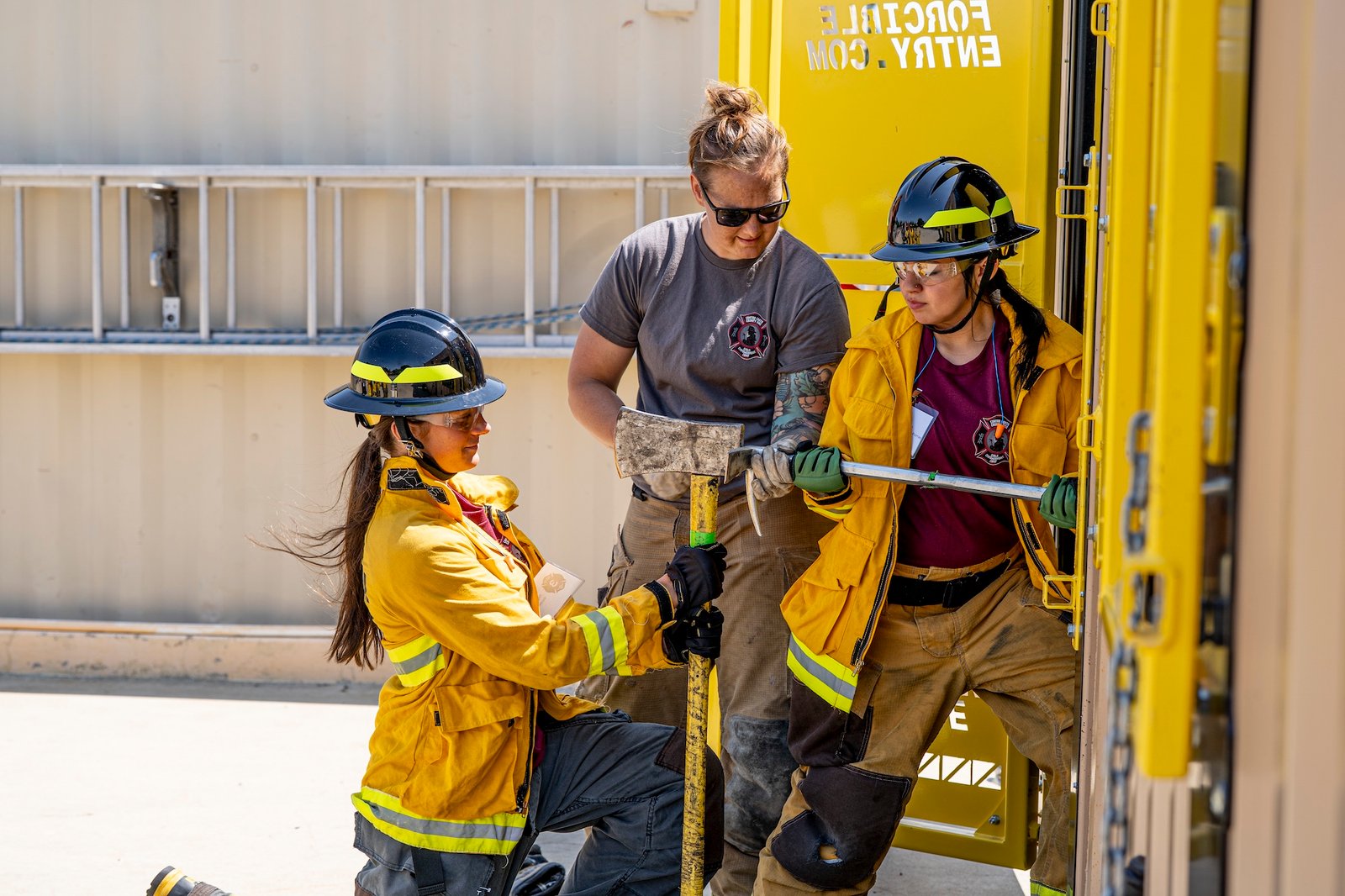 campers breaking open a door with a firefighters help