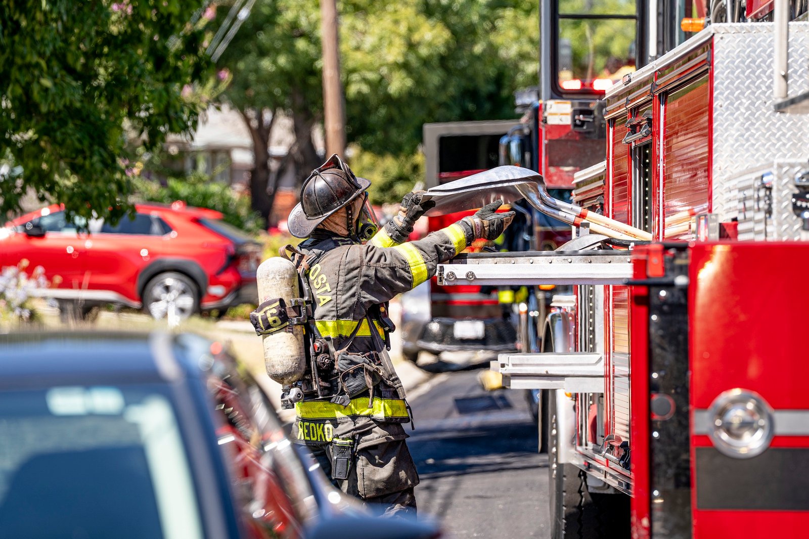firefighter reaching into a fire truck to access a tool