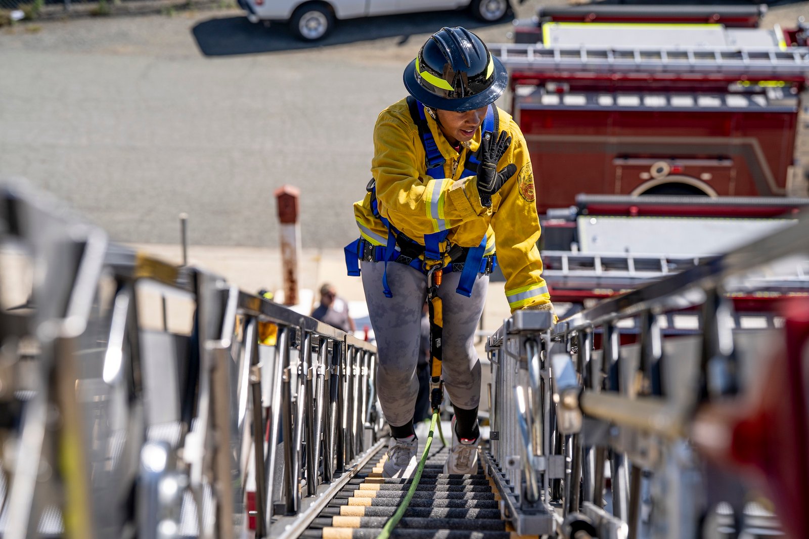 teen camper confidently waving on an aerial ladder